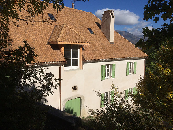 Photo de la façade sud avec les volets verts de la maison